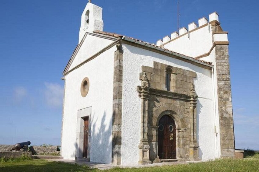 A white church with a bell tower, a stone archway, and a wooden door. 2