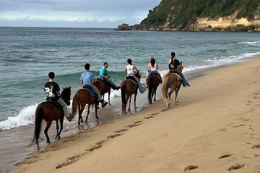 A beach with people riding horses along the shoreline. 3
