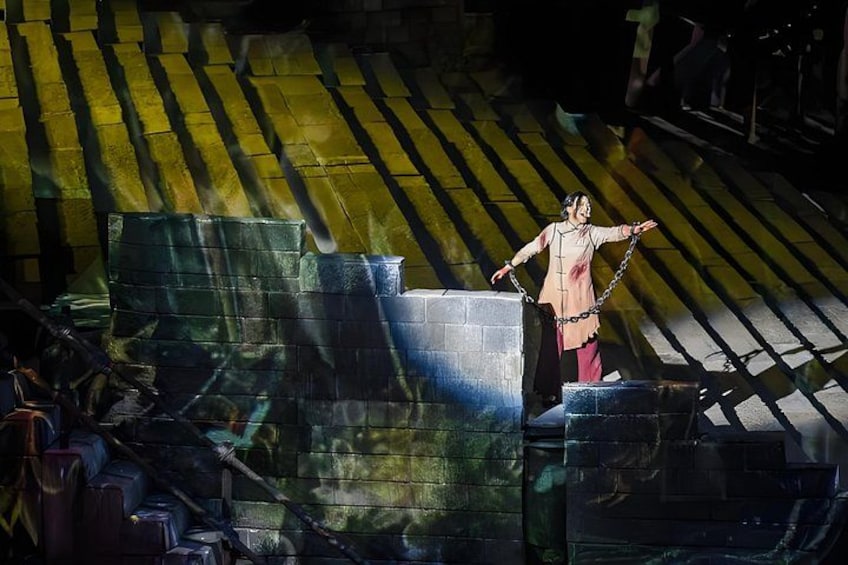 A person chained to a structure in an industrial setting with large blocks and a striped floor. 2