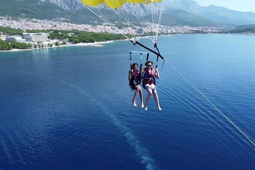 Three people parasailing over a body of water with a coastal town in the background. 3