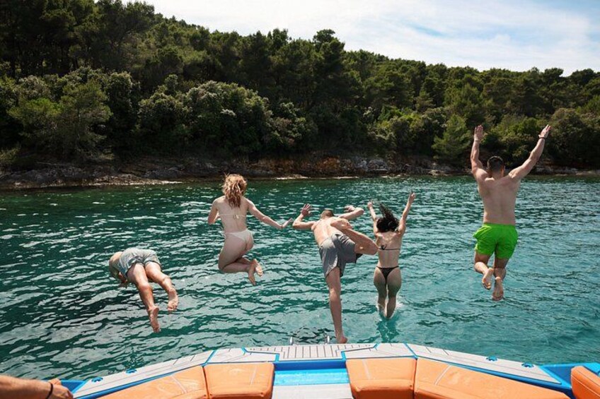 People jumping into a body of water surrounded by trees. 5
