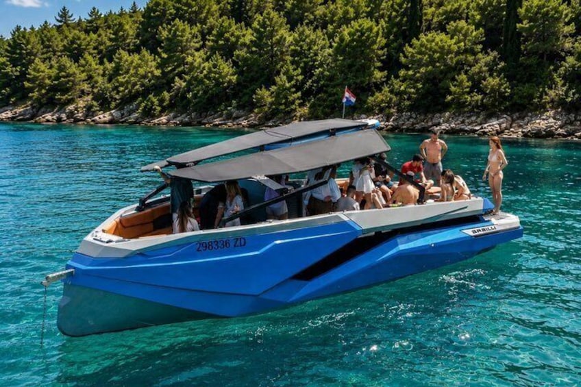A blue boat with people on board, surrounded by clear water and a forested shoreline. 1