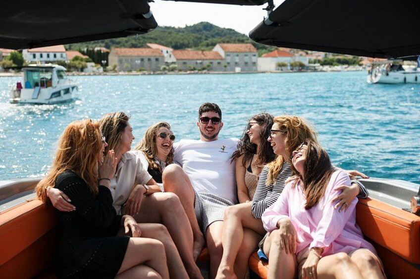 A group of people on a boat with a body of water and buildings in the background. 3