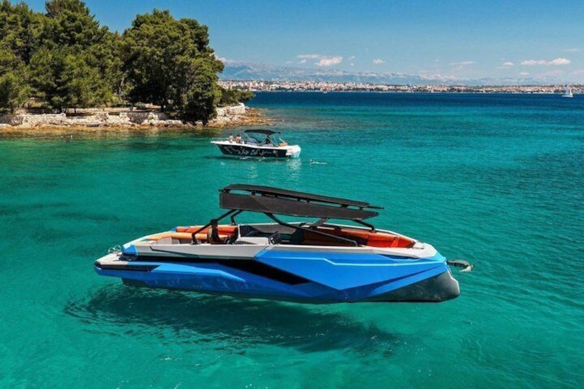 A blue speedboat on turquoise water with a rocky shoreline and trees in the background. 2