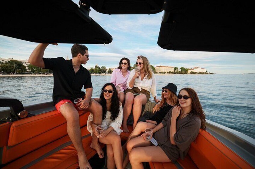 A group of people on a boat with a body of water and buildings in the background. 2