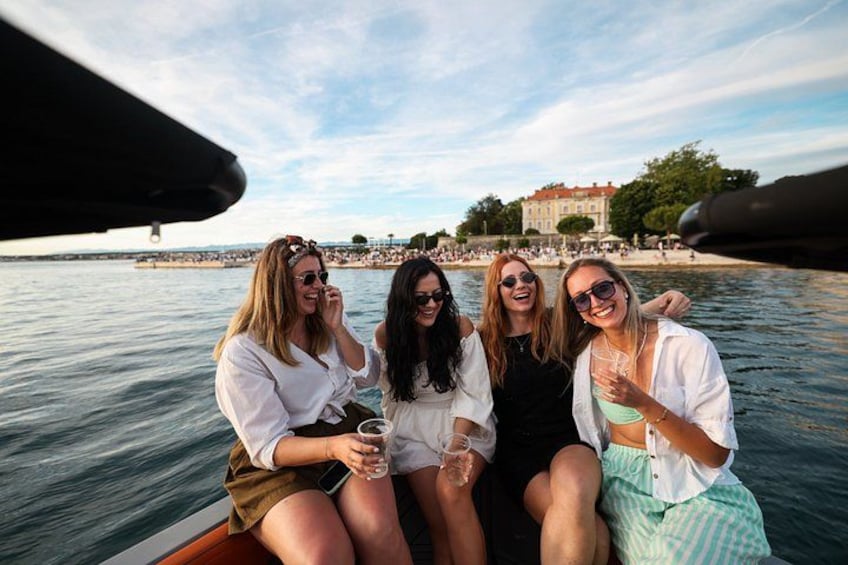 A group of people on a boat near a waterfront with buildings in the background. 2