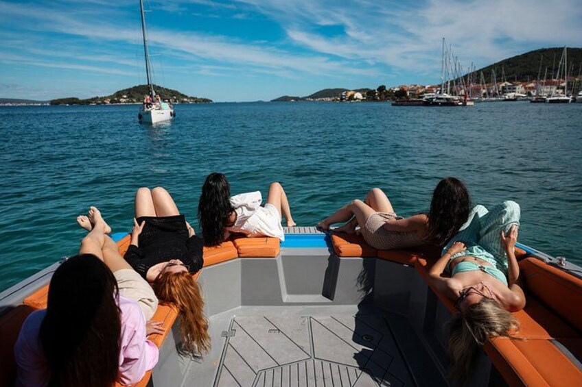 A group of people relaxing on a boat with a view of a marina and distant hills. 3