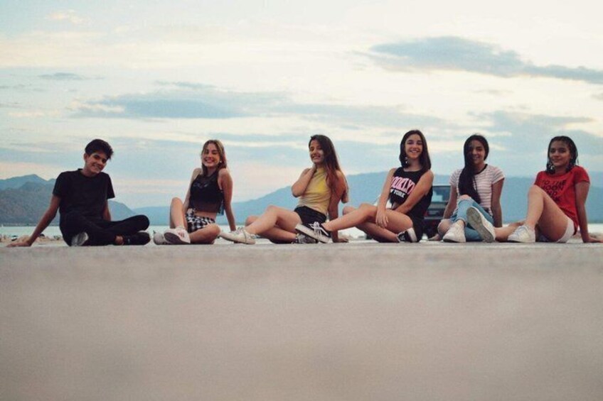 A group of five people sitting on a concrete ledge with a mountainous landscape in the background. 3