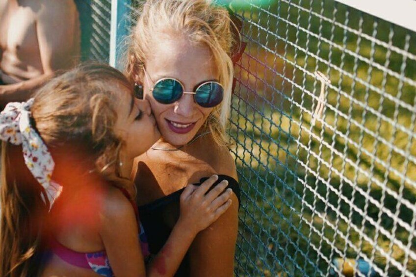 Two people embracing near a chain-link fence. 2