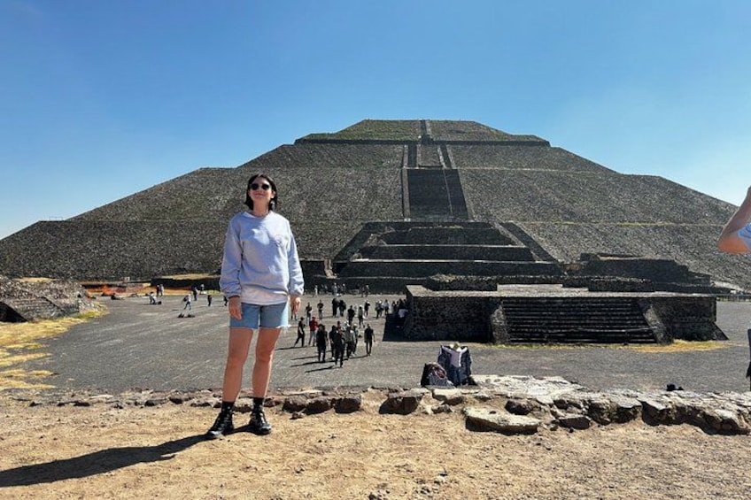 A person standing in front of a large pyramid with a clear sky. 1