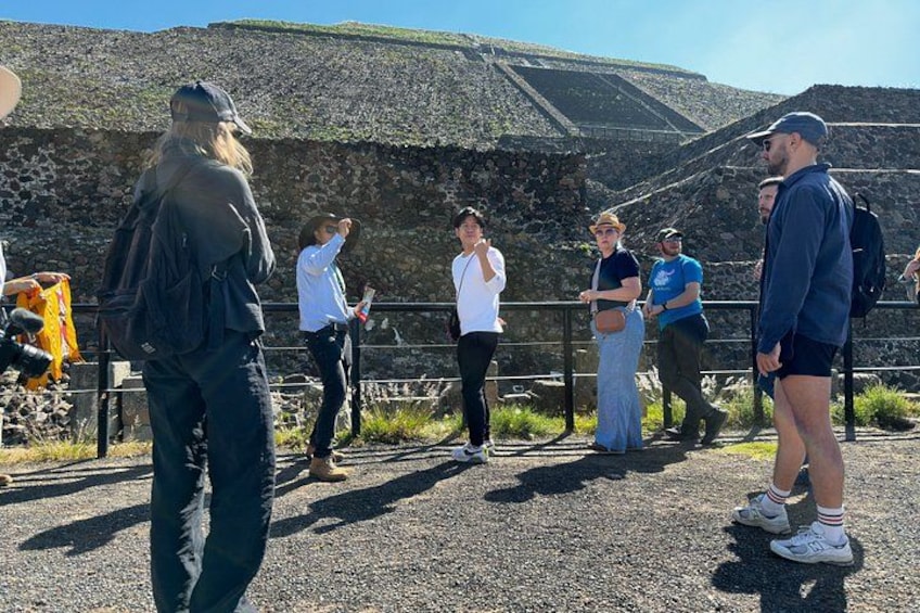 A group of people standing near a rocky landscape with a stone wall in the background. 4