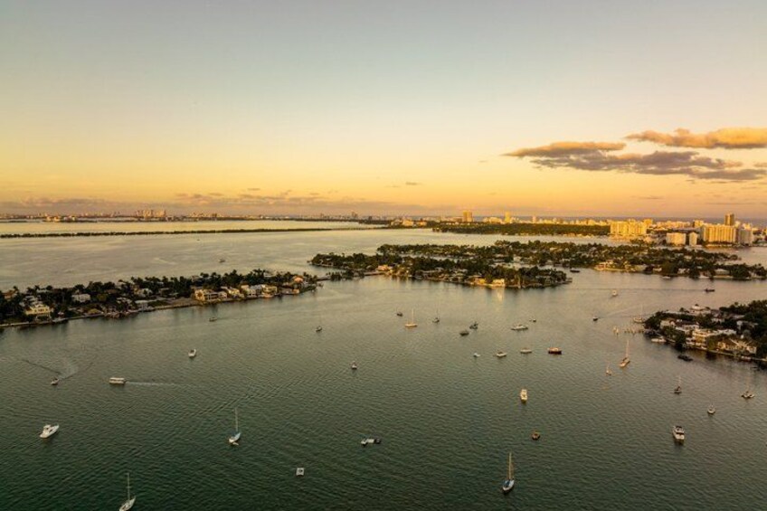 A coastal cityscape with a marina filled with boats, a distant city skyline, and a sunset. 2