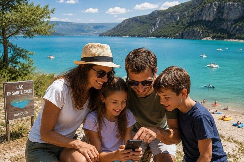 A family of four at a scenic beach with a sign reading 'LAC DE SAINTE-CROIX BAUDUEN.' 3