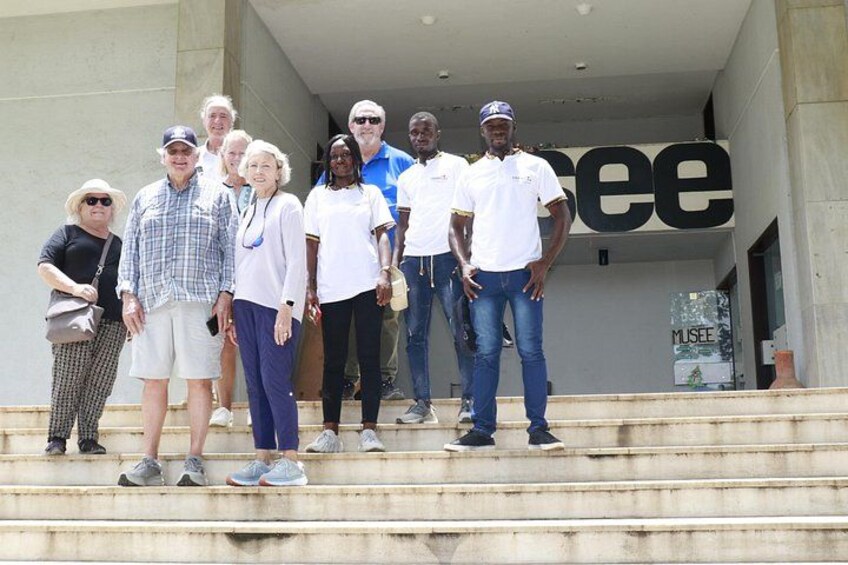 A group of people standing on steps in front of a building with a sign that reads 'MUSEE'. 4