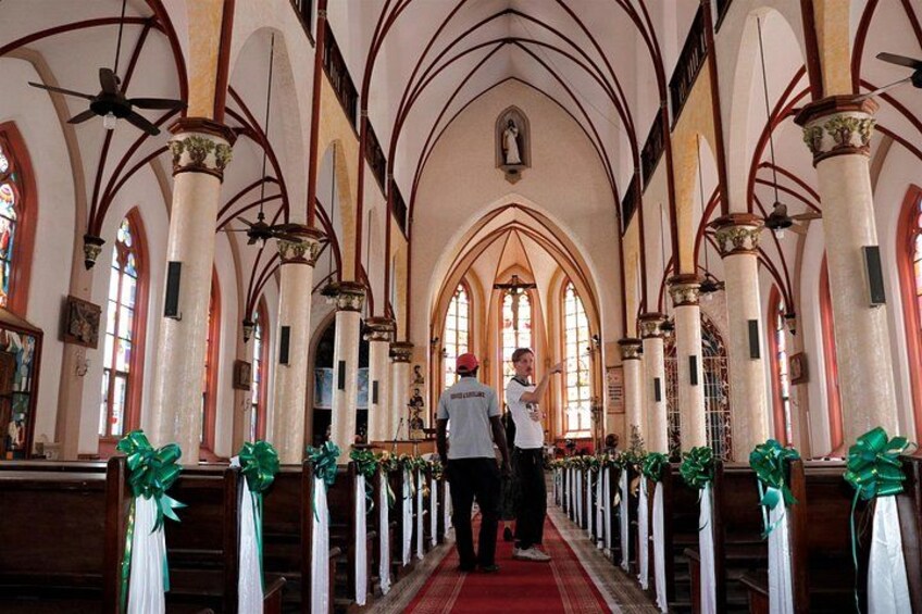 A church interior with arched ceilings, wooden pews, and green decorations. 5