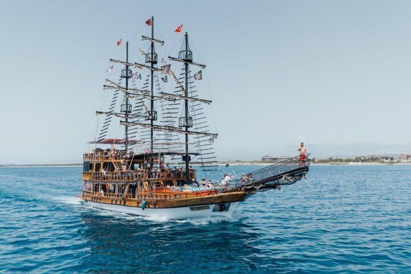 A tall ship with multiple masts and flags, sailing on a calm sea. 5