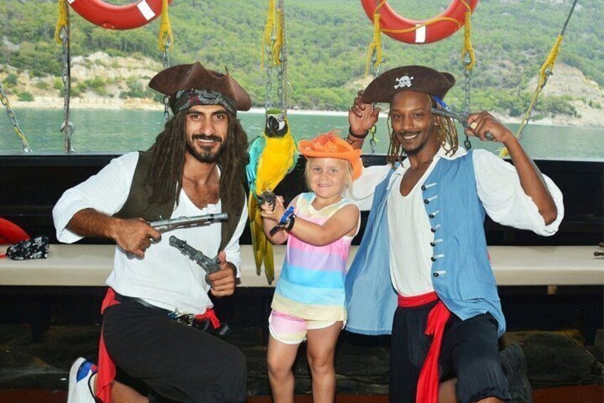 Two people in pirate costumes with a parrot on a boat. 1