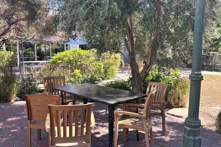 An outdoor patio with a table and chairs, surrounded by greenery and a lamp post. 3