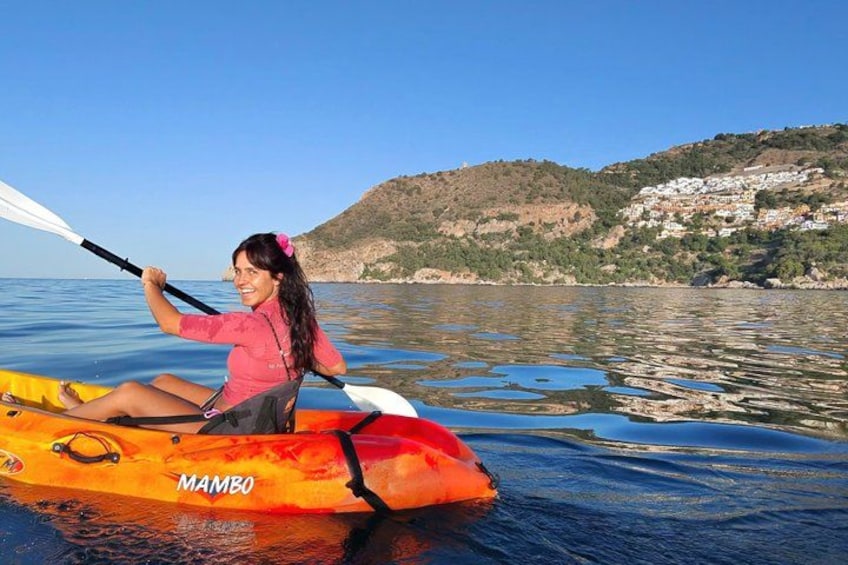 A person kayaking on a calm body of water with a hilly landscape in the background. 2