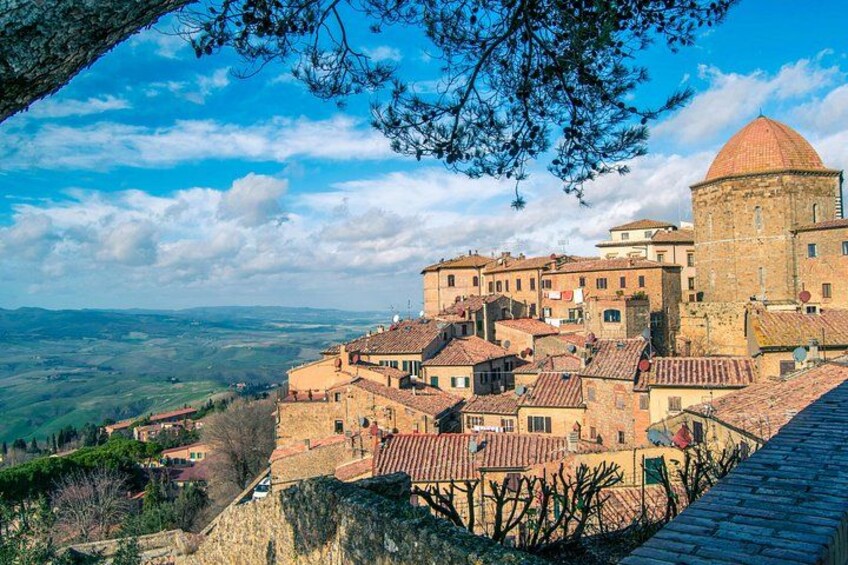 A historic town with stone buildings, a prominent tower, and a view of the surrounding countryside. 1