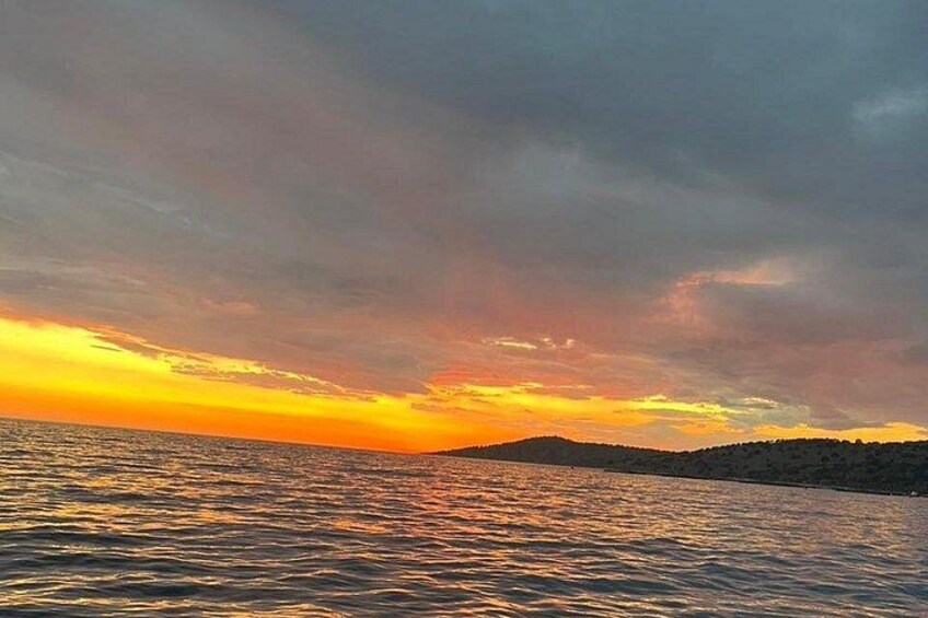 A sunset over a body of water with a hilly landscape in the background. 3