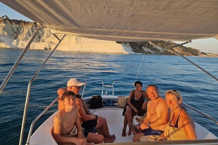 A group of people on a boat with a rocky coastline in the background. 2