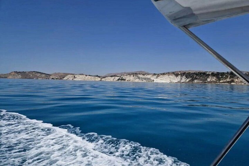 A boat on a calm sea with white cliffs in the background. 3