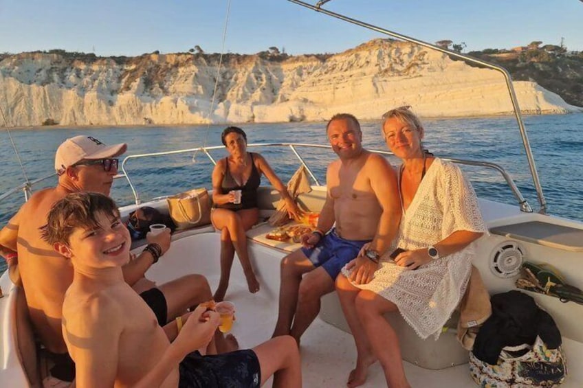A group of people on a boat with cliffs in the background. 1