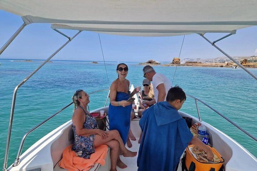 A boat with people on board, a clear blue sea, and rocky coastline in the background. 5