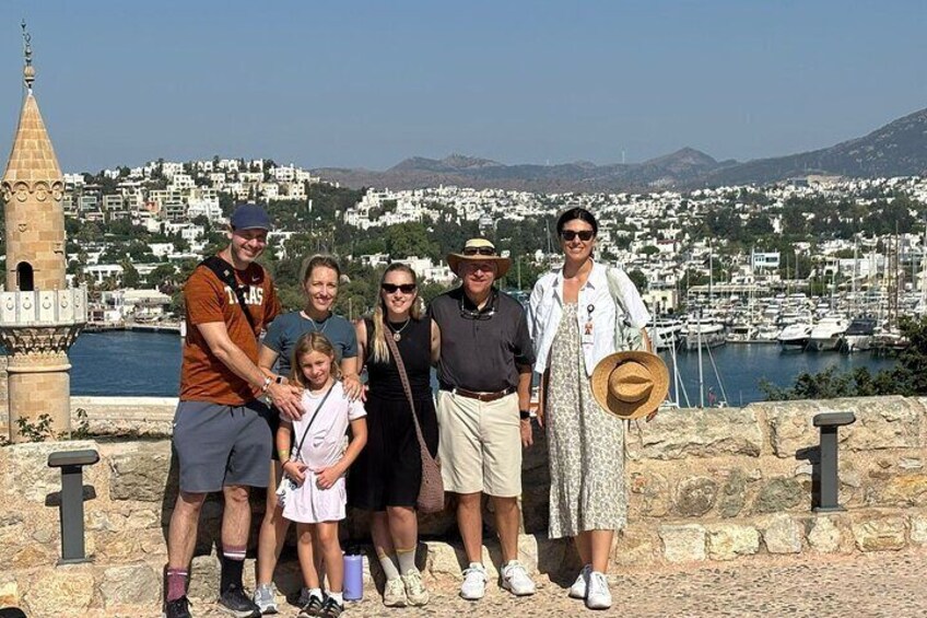 A group of people standing on a stone wall with a coastal town and a church in the background. 1