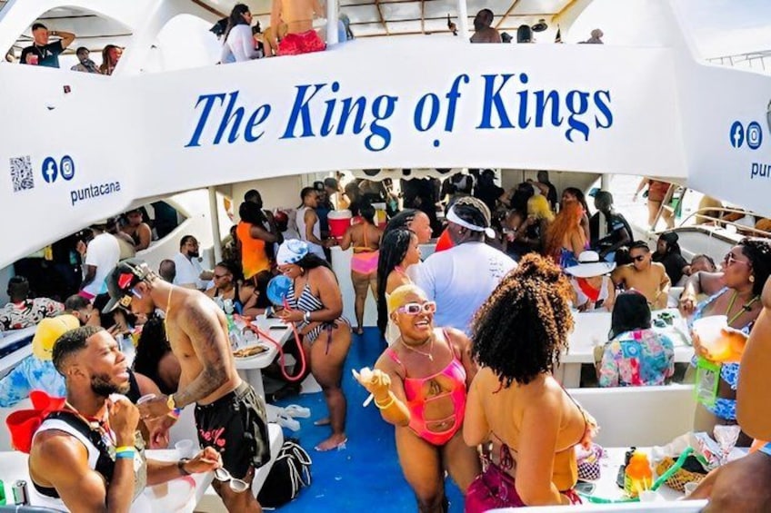 A boat with 'The King of Kings' written on it, filled with people enjoying a party. 1