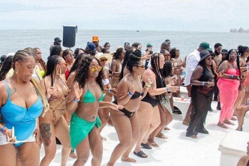 A group of people dancing on a boat with a body of water and distant land in the background. 4