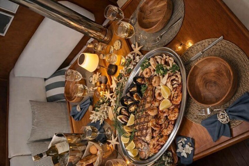 A seafood platter on a wooden table with glasses, plates, and a candle. 5