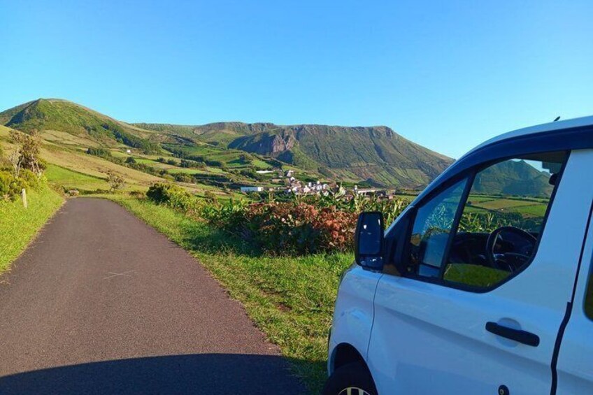 A white car parked on a rural road with a mountainous landscape in the background. 5