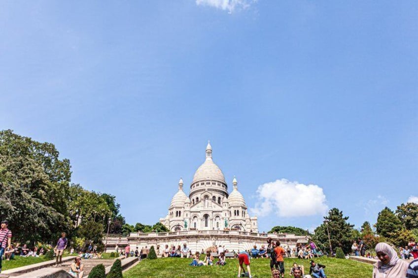 A large white domed building with multiple tiers, surrounded by a grassy area and trees. 2