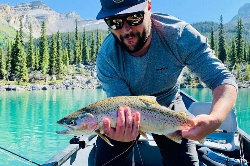 A person holding a fish on a boat with a mountainous landscape in the background. 2