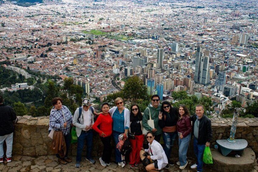 A group of people standing on a stone wall overlooking a cityscape with buildings and a river. 3