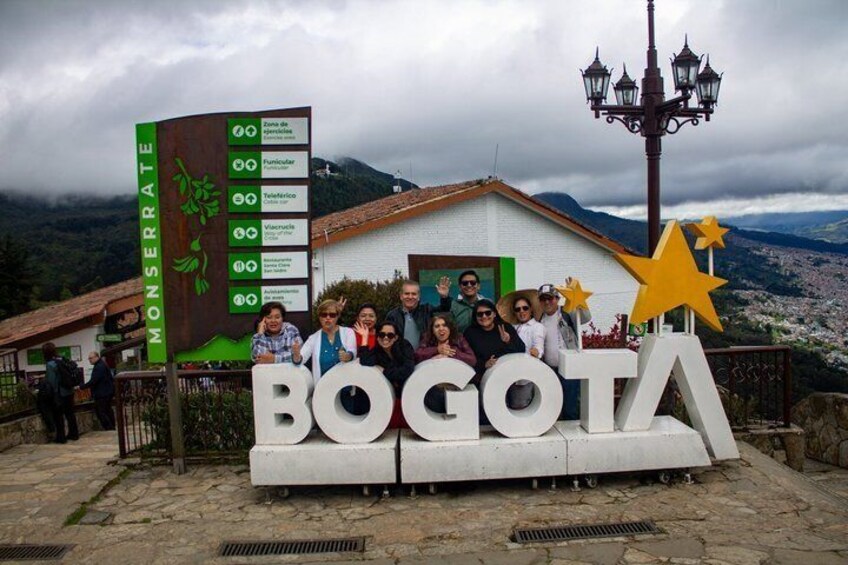 A group of people in front of a sign with 'BOGOTA' and a large star decoration. 2