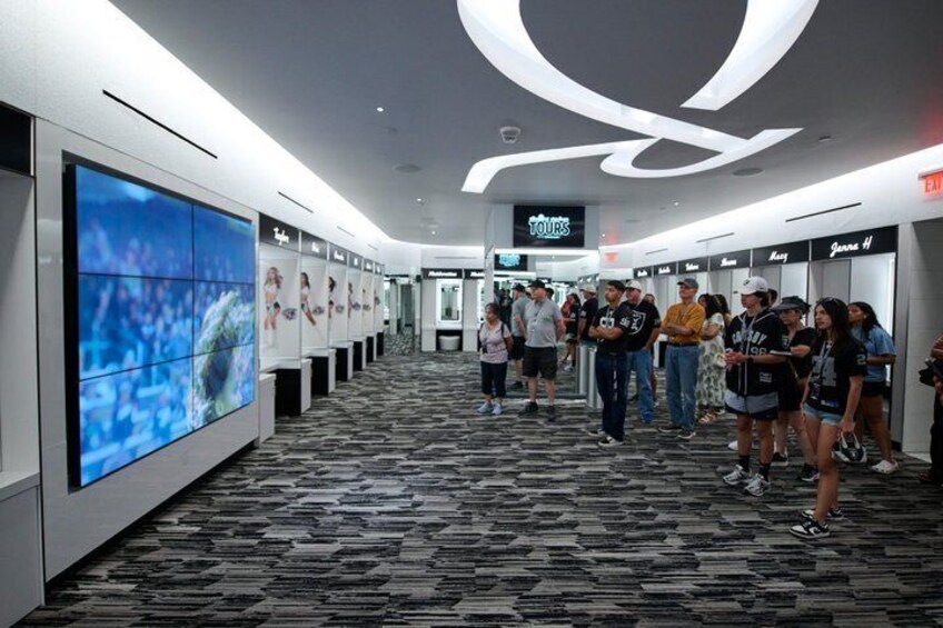 A hotel corridor with a large digital display, a 'TOURS' sign, and a carpeted floor. 4