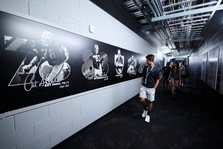 A hallway with a wall featuring sports memorabilia and a person standing in the foreground. 2