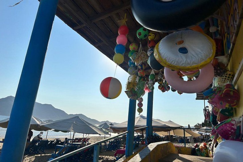 A beach with colorful beach balls and umbrellas, a clear sky, and mountains in the background. 4