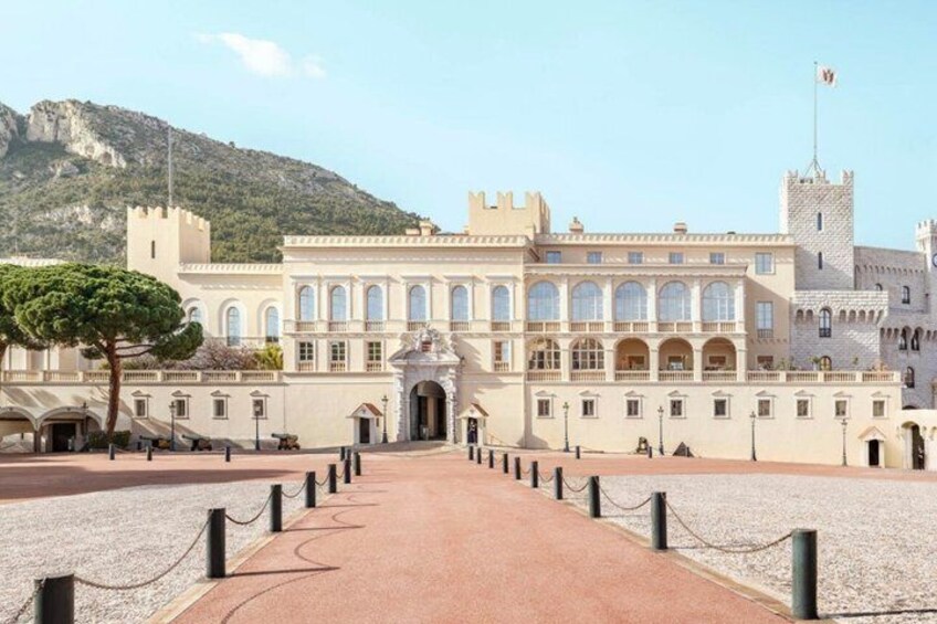 A historic building with a central courtyard, a flag, and a mountain in the background. 2