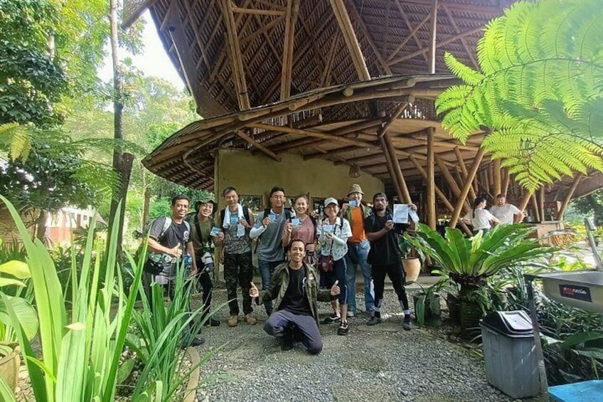 A group of people posing in a garden with a wooden structure and tropical plants. 3