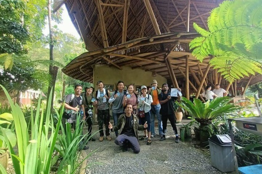 A group of people posing in a garden with a bamboo structure and tropical plants. 2