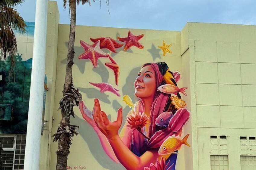 A mural with a woman surrounded by colorful fish and starfish. 1