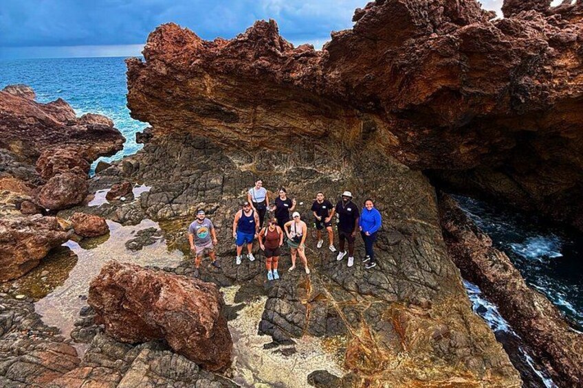 A group of people standing on rocky terrain near a body of water. 4