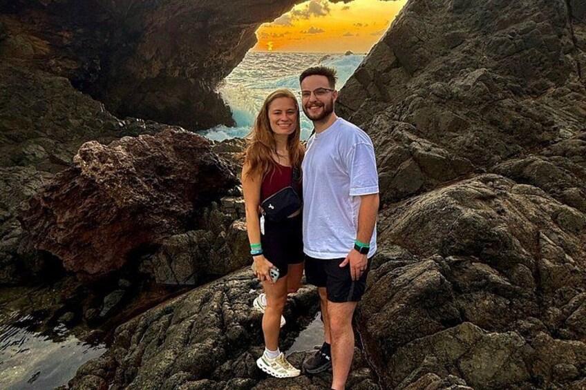 Two people standing on rocky terrain with a sunset in the background. 3