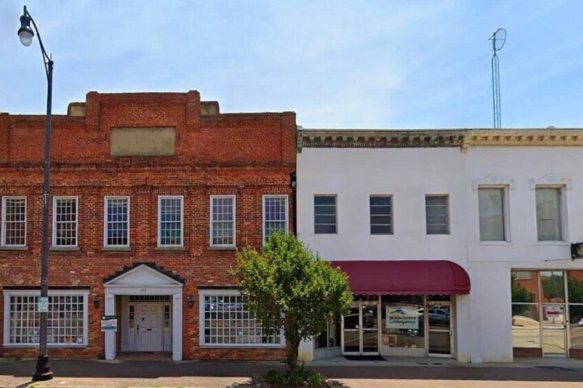 A street with a red brick building and a white building with a red awning. 2