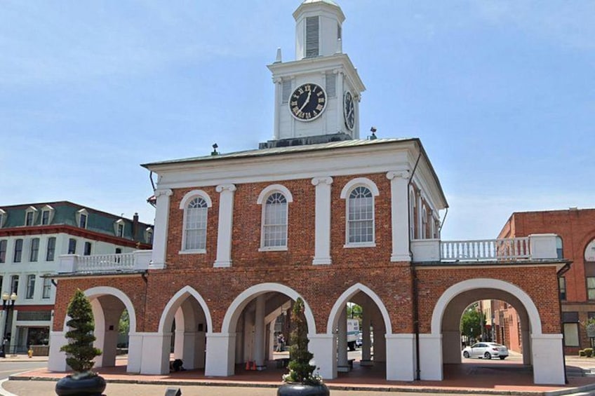 A historic building with a clock tower, arched windows, and a balcony. 4