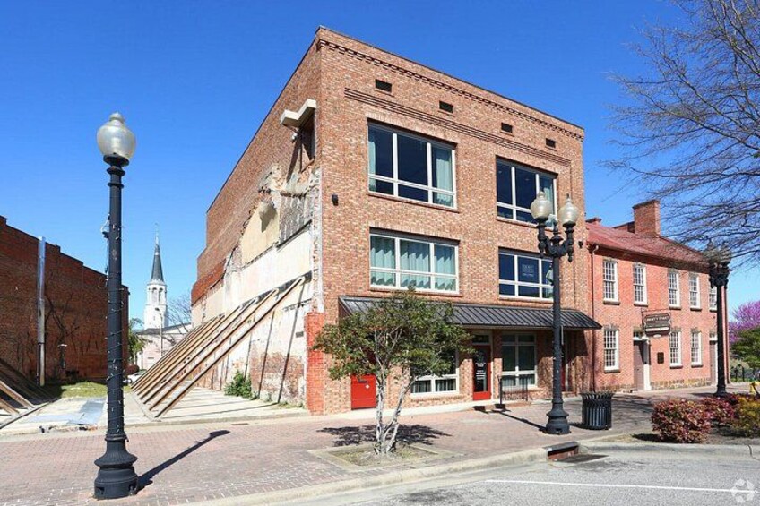 A historic brick building with a red door, a staircase leading to the entrance, and a street lamp. 3